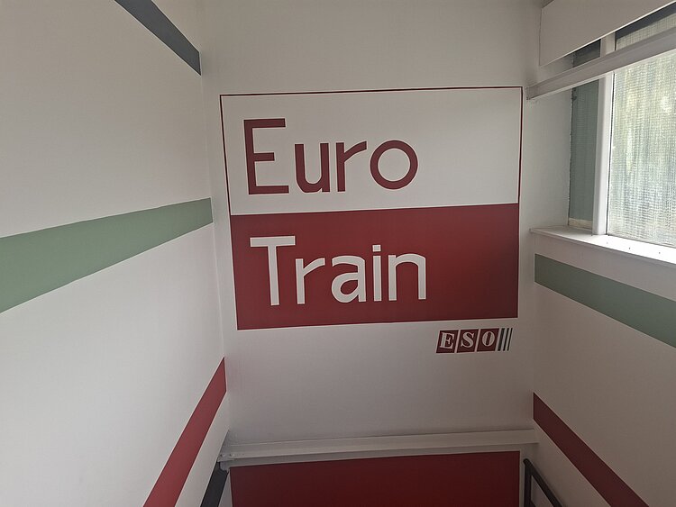 Auf einer Wand über einem Treppenhaus ist das Logo "Euro Train" und das ESO-Logo aufgemalt.